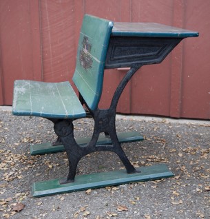 SOLD 

antique school desk.  wood and iron.  seat folds. ink well.  
red school house painting on back of seat.  
20.5" wide x 25" deep x 25" high